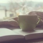 Une tasse de café repose sur un livre ouvert.