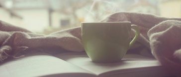 Une tasse de café repose sur un livre ouvert.