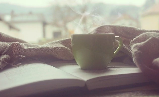 Une tasse de café repose sur un livre ouvert.