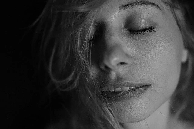 Une photo en noir et blanc d’une femme les yeux fermés.
