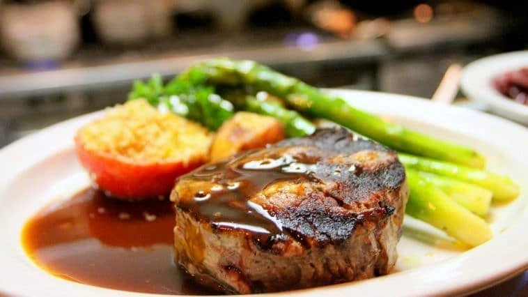 Une assiette avec un steak et des légumes dessus.