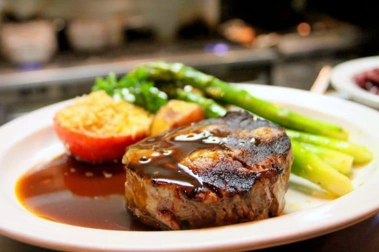 Une assiette avec un steak et des légumes dessus.