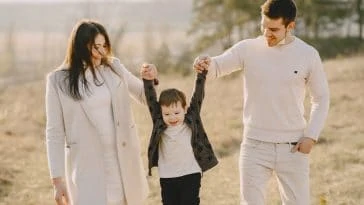 Une famille se tient la main en marchant dans un champ.