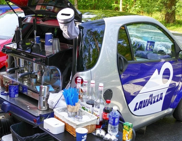 Une petite voiture avec une machine à café à l'arrière.