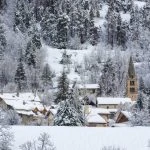 Un village enneigé avec des arbres en arrière-plan.