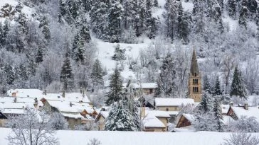 Un village enneigé avec des arbres en arrière-plan.