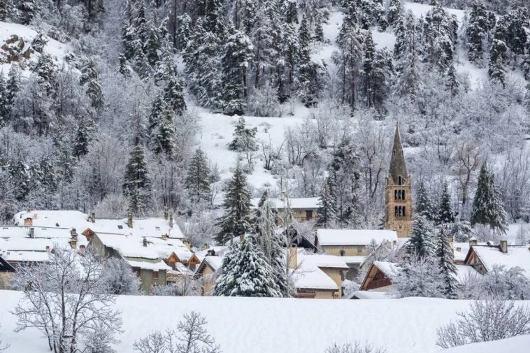 Un village enneigé avec des arbres en arrière-plan.