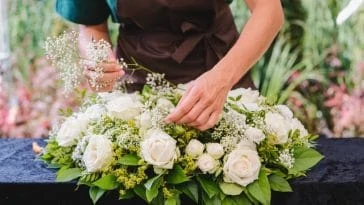 Un fleuriste arrange des roses blanches sur une table.