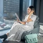 Une femme assise sur un fauteuil poire avec une tablette parcourant des conseils de mode.