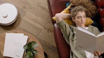 Une femme allongée sur un canapé en train de lire un livre.