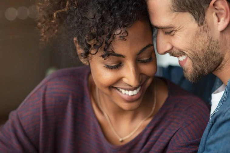 Un couple se sourit tout en regardant un ordinateur portable, mettant en valeur l'amour et l'authenticité.