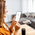 Une femme utilise son téléphone intelligent pour contrôler sa maison intelligente.