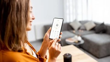 Une femme utilise son téléphone intelligent pour contrôler sa maison intelligente.