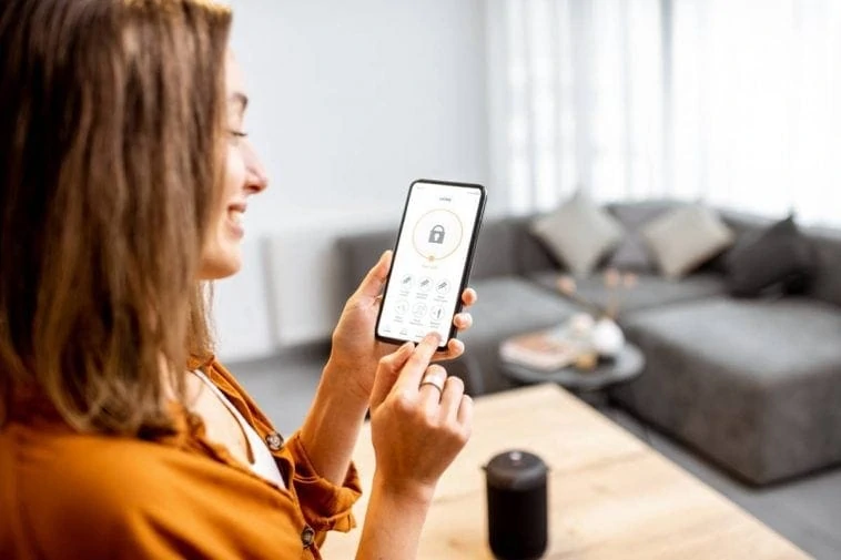 Une femme utilise son téléphone intelligent pour contrôler sa maison intelligente.