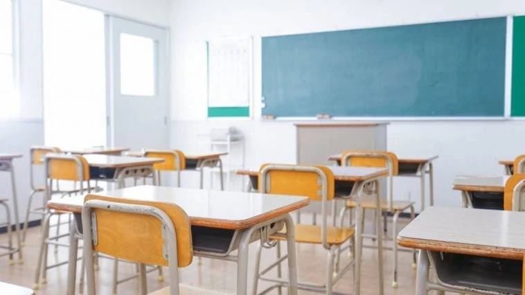 Une salle de classe vide avec des chaises et un tableau blanc interactif.