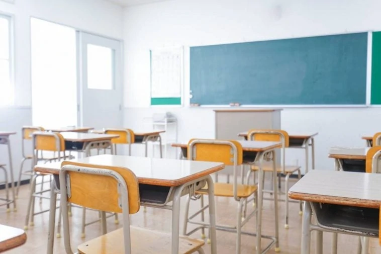 Une salle de classe vide avec des chaises et un tableau blanc interactif.