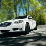 Une Opel Insignia blanche conduisant sur une route.