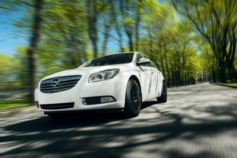 Une Opel Insignia blanche conduisant sur une route.