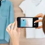 Une femme capturant l’essence de la mode durable en photographiant des vêtements de seconde main sur un portant.