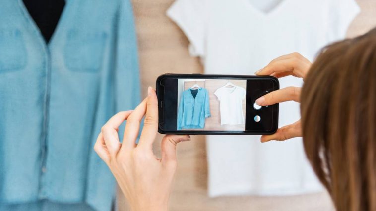 Une femme capturant l’essence de la mode durable en photographiant des vêtements de seconde main sur un portant.