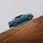 Un Ford Raptor bleu descend une colline.