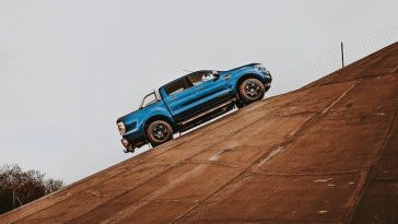 Un Ford Raptor bleu descend une colline.