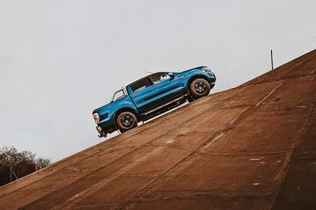 Un Ford Raptor bleu descend une colline.