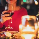 Une femme tient un verre de vin dans un restaurant. L'étiquette à table