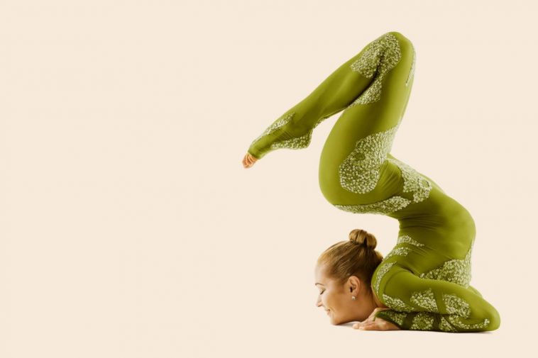 Une femme pratiquant le yoga sur fond beige.