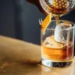 Une personne versant un old fashioned dans un verre.