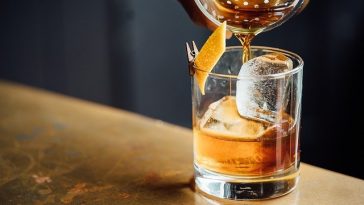 Une personne versant un old fashioned dans un verre.