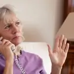 Une femme âgée utilisant un téléphone fixe.