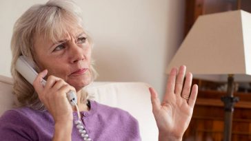 Une femme âgée utilisant un téléphone fixe.