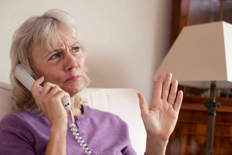 Une femme âgée utilisant un téléphone fixe.