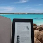 Un Kindle est posé sur un rocher face à l'océan, soulignant les avantages et les différences par rapport au format PDF/A.