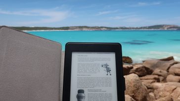 Un Kindle est posé sur un rocher face à l'océan, soulignant les avantages et les différences par rapport au format PDF/A.