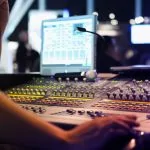 Tout savoir sur le mixage audio d'une personne travaillant sur une console de mixage.