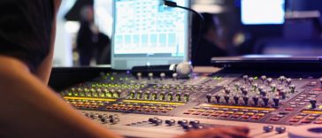 Tout savoir sur le mixage audio d'une personne travaillant sur une console de mixage.