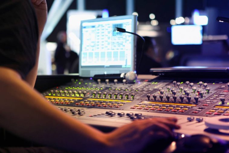 Tout savoir sur le mixage audio d'une personne travaillant sur une console de mixage.