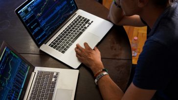 Un homme découvre la Bourse et négocie avec deux ordinateurs portables.