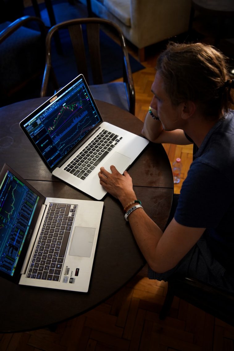 Un homme découvre la Bourse et négocie avec deux ordinateurs portables.