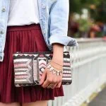 Une femme portant une veste en jean et une jupe bordeaux.