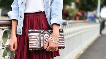 Une femme portant une veste en jean et une jupe bordeaux.