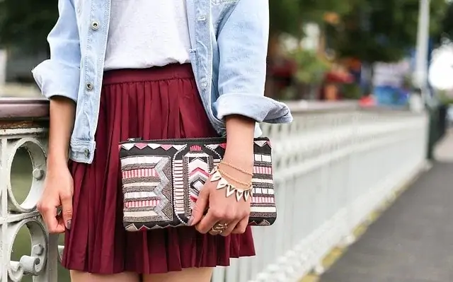 Une femme portant une veste en jean et une jupe bordeaux.