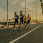 Un groupe de coureurs sur un pont participant à un événement sportif.