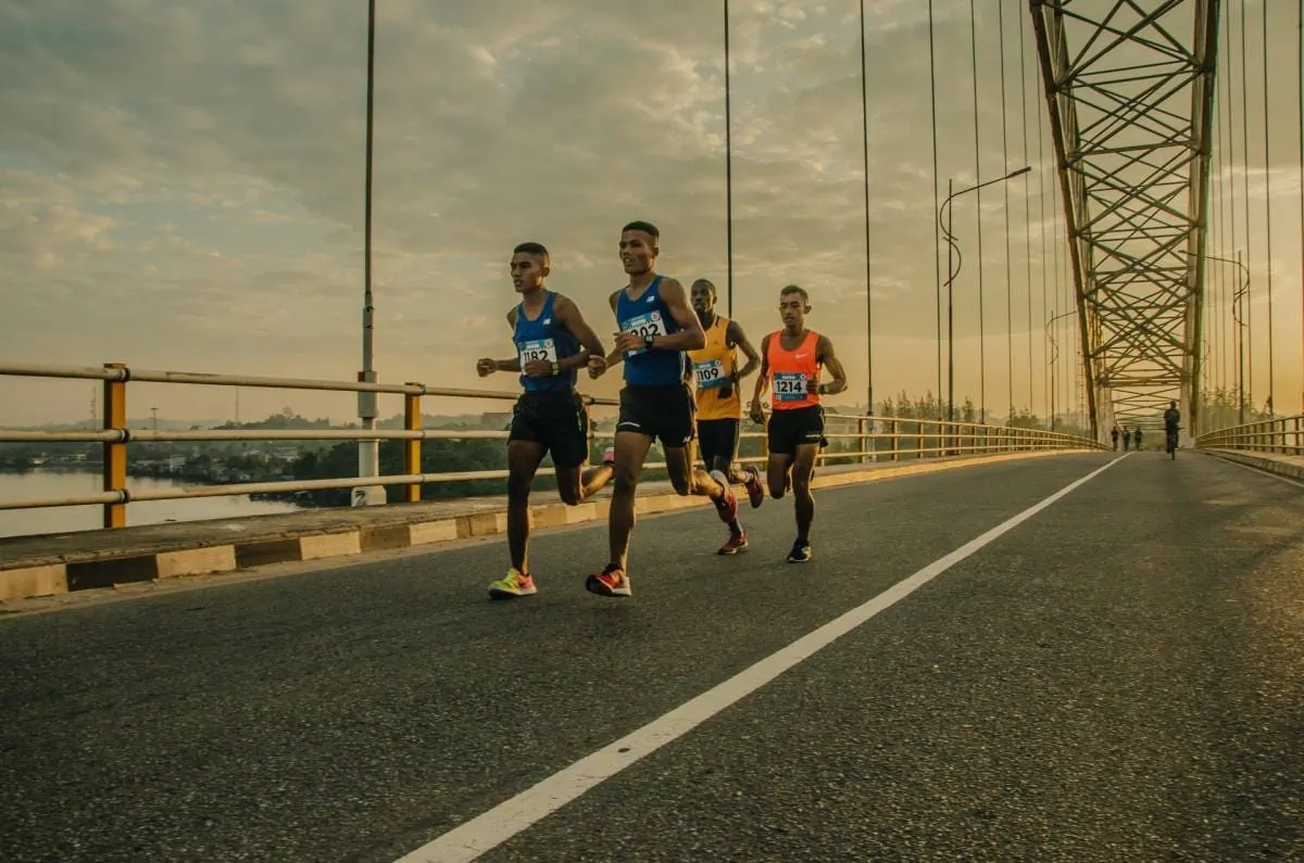 Un groupe de coureurs sur un pont participant à un événement sportif.