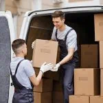 Deux hommes chargeant des cartons dans une camionnette de déménagement.