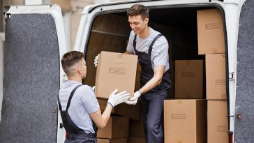 Deux hommes chargeant des cartons dans une camionnette de déménagement.