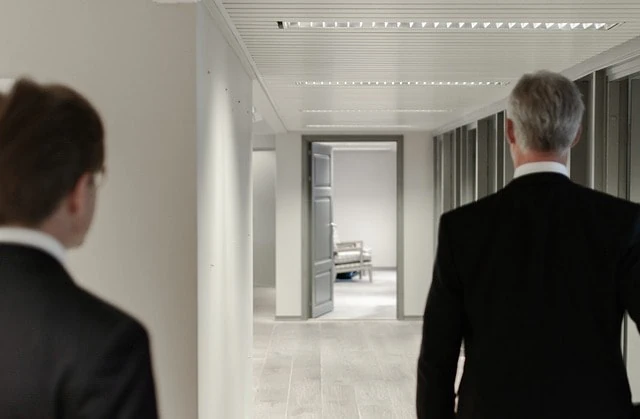 Deux hommes en costume marchant dans un couloir.