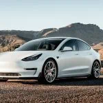 Une Tesla Model 3 blanche garée sur une route du désert.